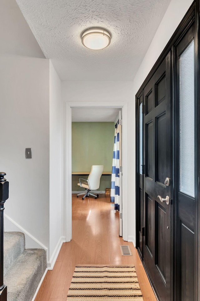 hall featuring a textured ceiling and light hardwood / wood-style flooring