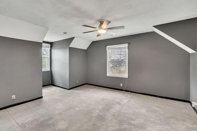 additional living space featuring plenty of natural light, light carpet, a textured ceiling, and ceiling fan