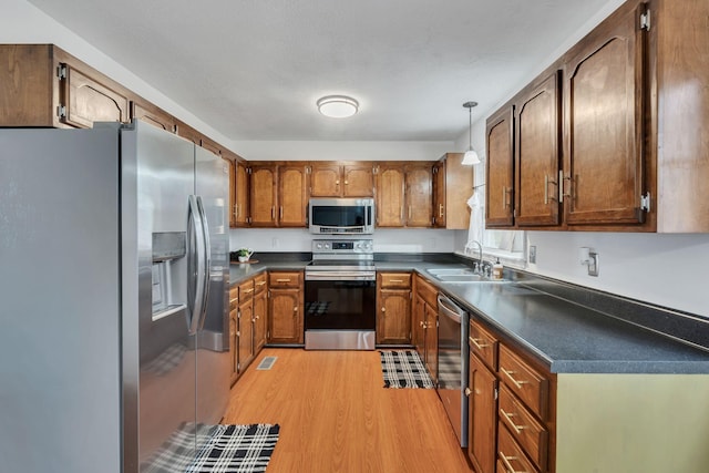 kitchen featuring hanging light fixtures, appliances with stainless steel finishes, sink, and light hardwood / wood-style floors