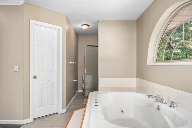 bathroom featuring tiled bath, toilet, and tile patterned floors