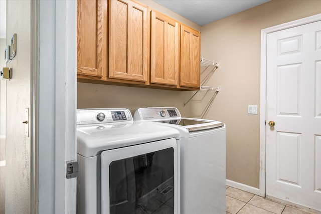 washroom featuring light tile patterned flooring, washing machine and clothes dryer, and cabinets