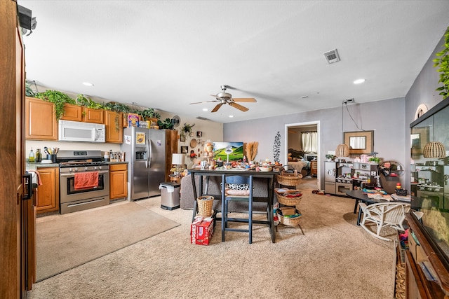 kitchen featuring appliances with stainless steel finishes, hanging light fixtures, ceiling fan, and light colored carpet