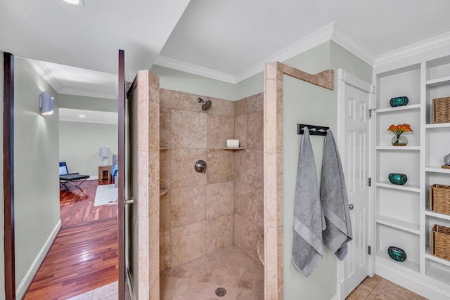 bathroom with ornamental molding, built in shelves, a tile shower, and hardwood / wood-style floors