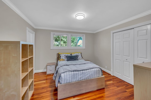 bedroom featuring light hardwood / wood-style floors, ornamental molding, and a closet