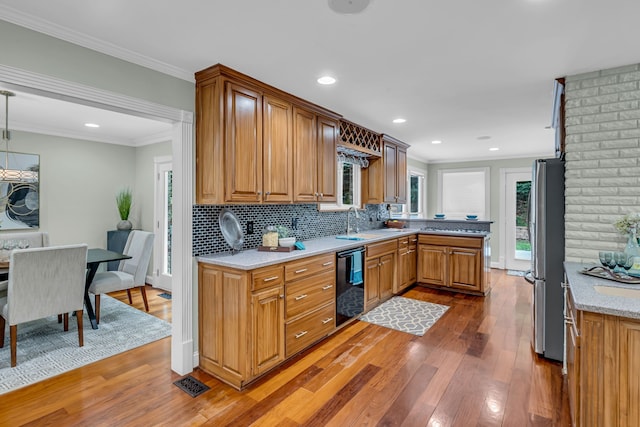 kitchen featuring dishwasher, hardwood / wood-style flooring, tasteful backsplash, decorative light fixtures, and stainless steel fridge