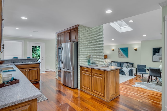 kitchen featuring a kitchen island, stainless steel appliances, light hardwood / wood-style flooring, a skylight, and sink