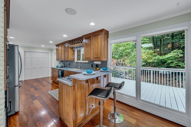 kitchen featuring stainless steel refrigerator, backsplash, a kitchen bar, dark hardwood / wood-style floors, and sink