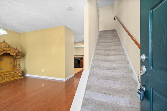 stairway with a textured ceiling and hardwood / wood-style floors