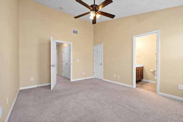 unfurnished bedroom with light carpet, ensuite bathroom, and ceiling fan