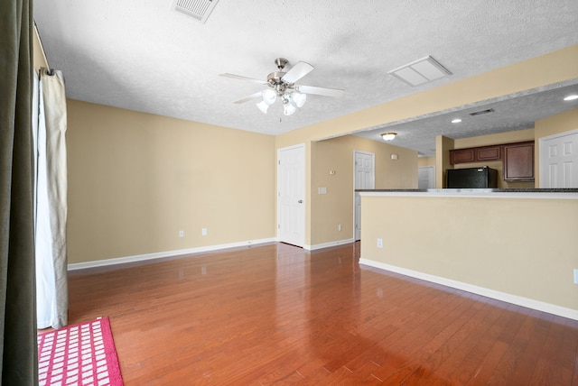 unfurnished living room featuring a textured ceiling, dark hardwood / wood-style flooring, and ceiling fan