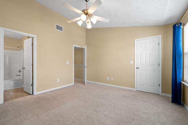 unfurnished bedroom featuring connected bathroom, lofted ceiling, and light colored carpet