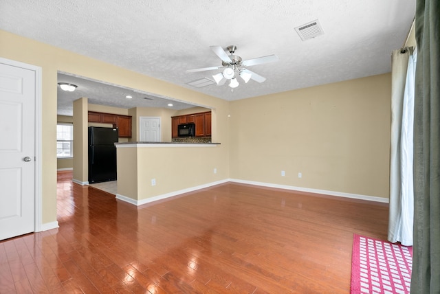 unfurnished living room with wood-type flooring, a textured ceiling, and ceiling fan