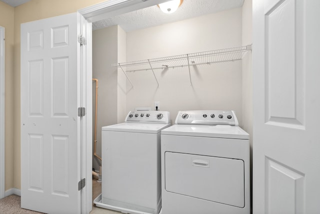 laundry room with light carpet, a textured ceiling, and washing machine and dryer