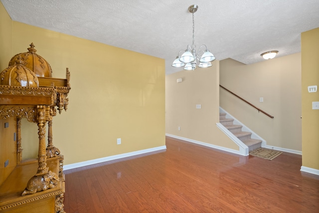 unfurnished living room with a textured ceiling, hardwood / wood-style floors, and a chandelier