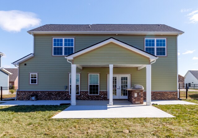 rear view of property featuring a patio, a lawn, and french doors