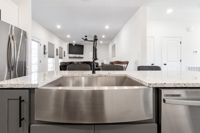 kitchen with light stone counters, sink, ceiling fan, and appliances with stainless steel finishes