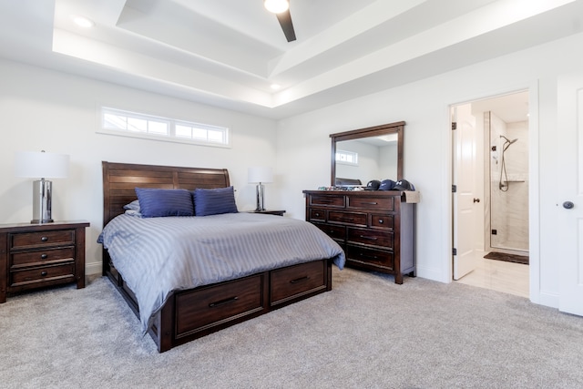 carpeted bedroom with ceiling fan, ensuite bathroom, and a raised ceiling