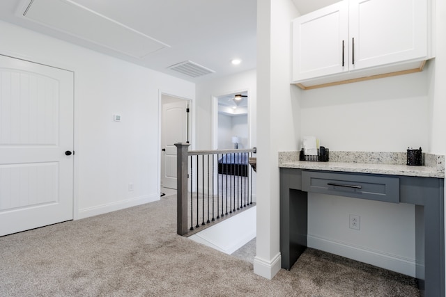 kitchen with light stone counters, light colored carpet, gray cabinets, and white cabinets