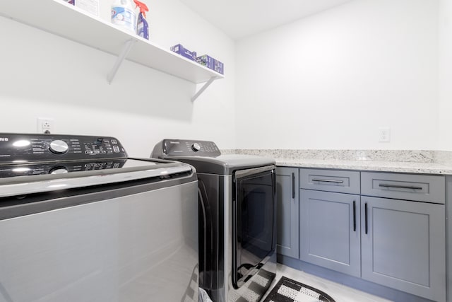 clothes washing area with cabinets and washer and clothes dryer