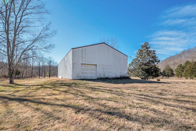 view of outdoor structure featuring a rural view, a yard, and a garage