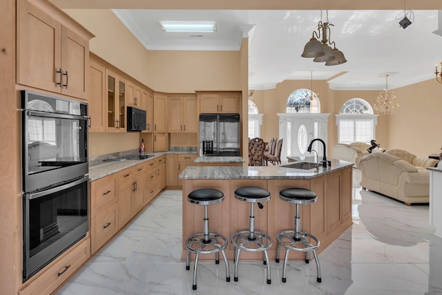 kitchen featuring a breakfast bar, ornamental molding, black appliances, an island with sink, and decorative light fixtures