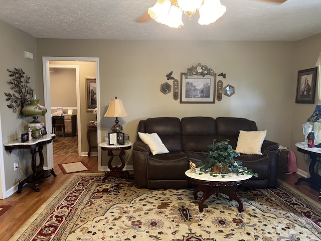 living room with ceiling fan, a textured ceiling, and hardwood / wood-style floors