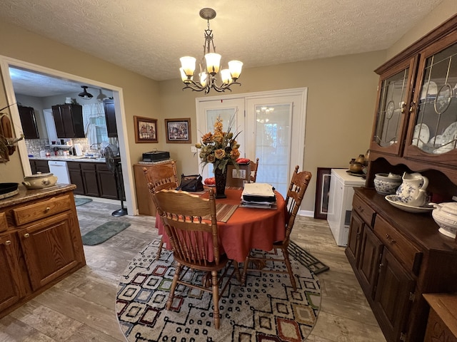 dining space featuring an inviting chandelier, light wood-type flooring, and a textured ceiling