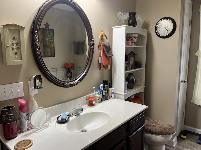 bathroom with wood-type flooring, vanity, and toilet