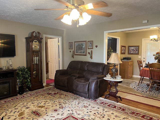 living room featuring wood-type flooring, a textured ceiling, and ceiling fan with notable chandelier