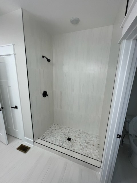 bathroom featuring tiled shower and toilet