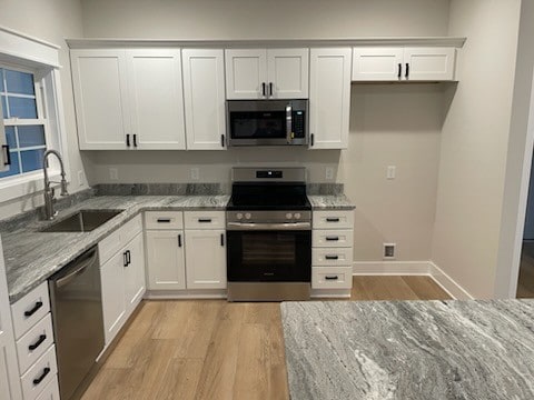 kitchen featuring light stone counters, appliances with stainless steel finishes, and white cabinetry