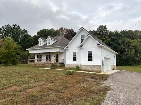 view of front of house with a front lawn, covered porch, and a garage