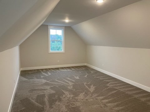 bonus room featuring dark colored carpet and vaulted ceiling