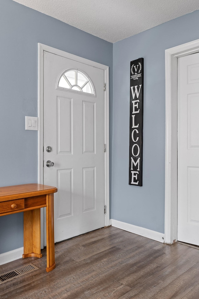 entryway with dark wood-type flooring and a textured ceiling