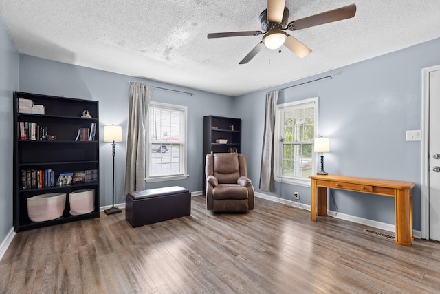 sitting room featuring wood-type flooring, a textured ceiling, and ceiling fan