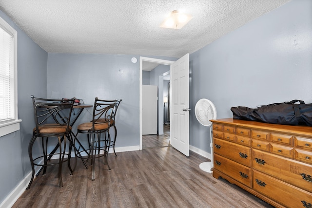 bedroom featuring white refrigerator, dark hardwood / wood-style flooring, and a textured ceiling