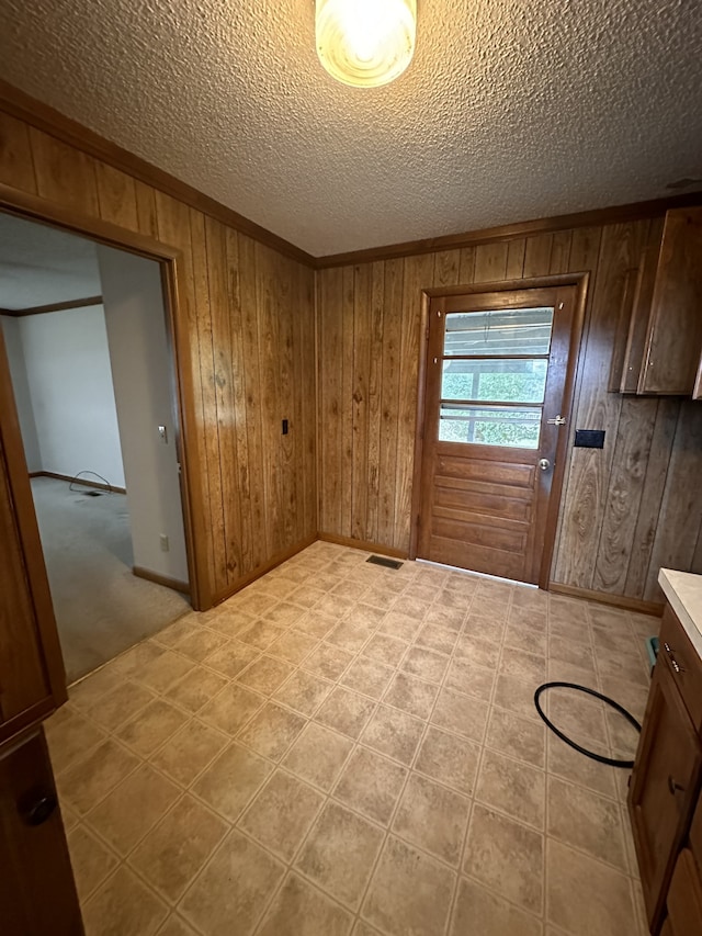 doorway to outside featuring a textured ceiling and wooden walls