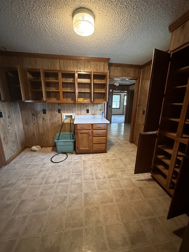 kitchen with built in desk, a textured ceiling, and wood walls