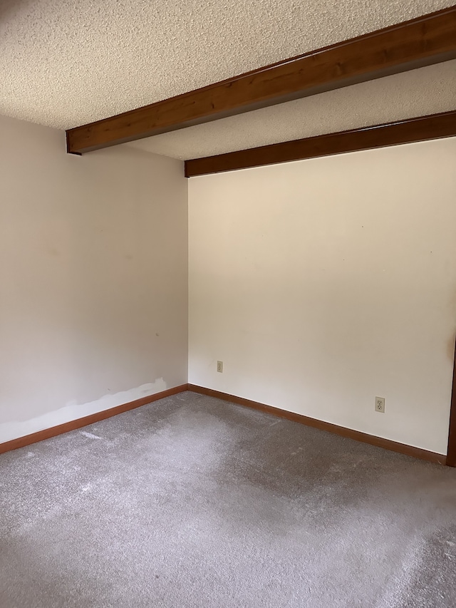 unfurnished room featuring a textured ceiling, carpet flooring, and beam ceiling