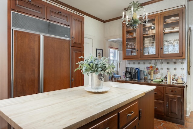 kitchen featuring ornamental molding, backsplash, paneled built in fridge, an inviting chandelier, and tile patterned flooring