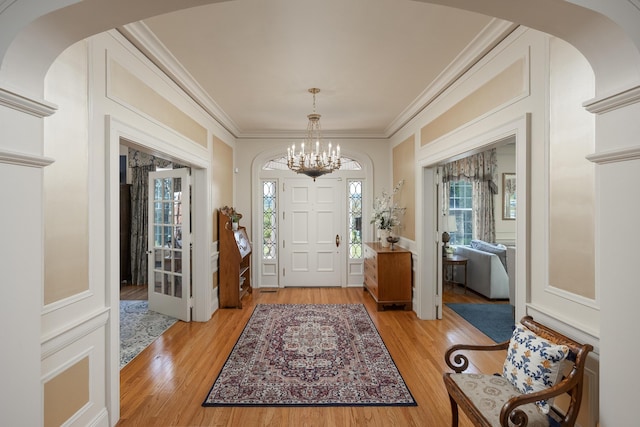 foyer entrance featuring ornamental molding, a chandelier, and light hardwood / wood-style floors