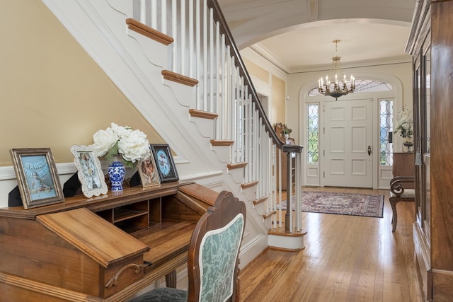 foyer with light hardwood / wood-style flooring, an inviting chandelier, and ornamental molding