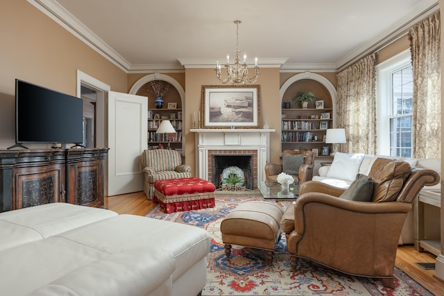 living room featuring a notable chandelier, built in features, a brick fireplace, and hardwood / wood-style flooring