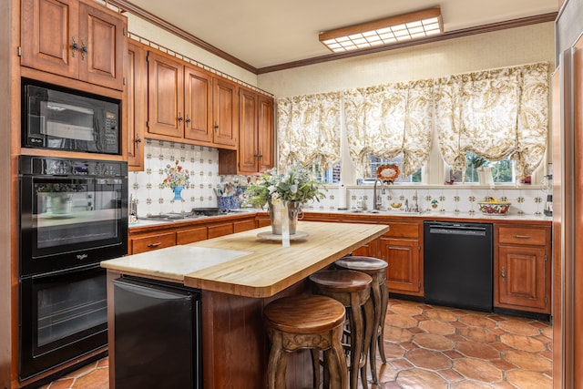 kitchen featuring a kitchen island, crown molding, black appliances, sink, and wood counters