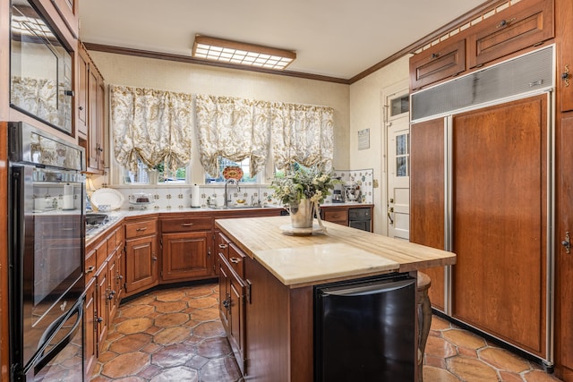 kitchen featuring sink, wooden counters, double oven, a center island, and crown molding