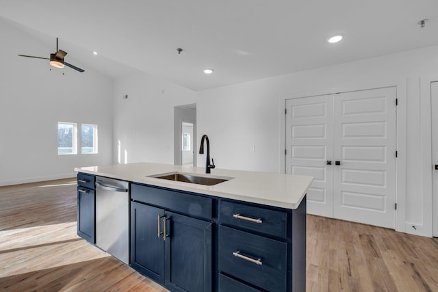 kitchen featuring a kitchen island with sink, sink, stainless steel dishwasher, ceiling fan, and light wood-type flooring