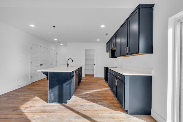 kitchen featuring range with electric stovetop, a kitchen island with sink, light hardwood / wood-style flooring, and sink