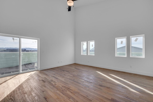 unfurnished living room featuring a high ceiling, ceiling fan, and hardwood / wood-style floors