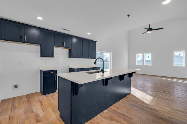 kitchen with a kitchen breakfast bar, light wood-type flooring, ceiling fan, sink, and a center island with sink