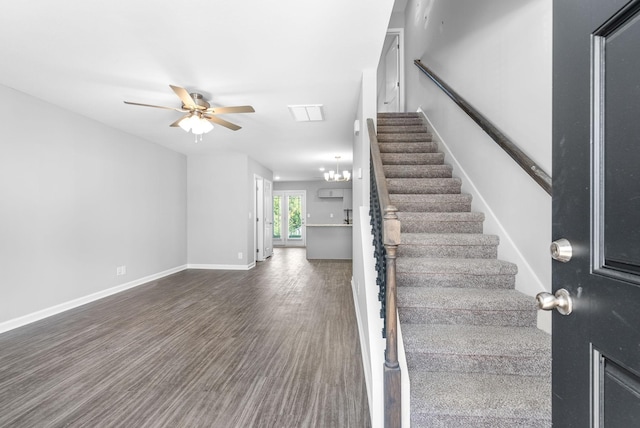 stairway featuring wood finished floors, baseboards, and ceiling fan with notable chandelier